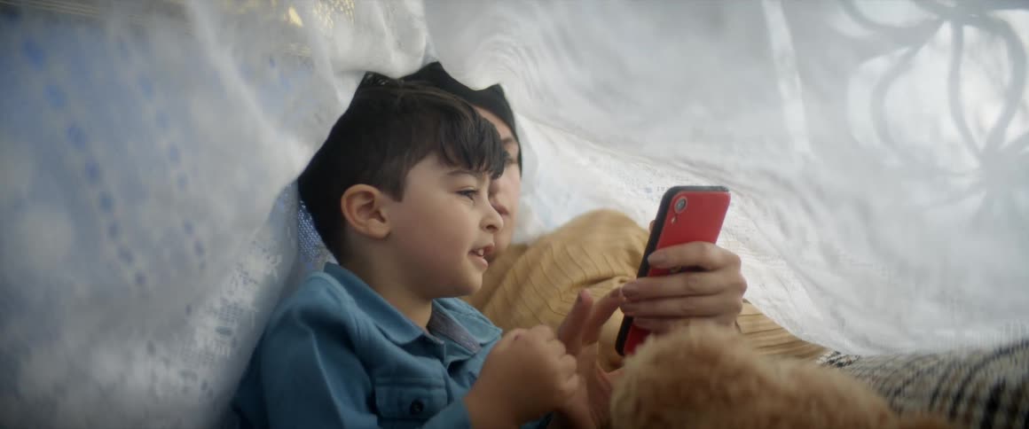 Mother and son in a homemade tent on playing with phone
