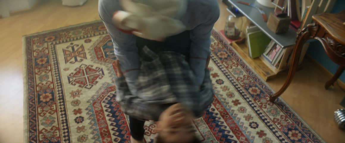 A person holds a male toddlers legs around their hips and spins them in circles