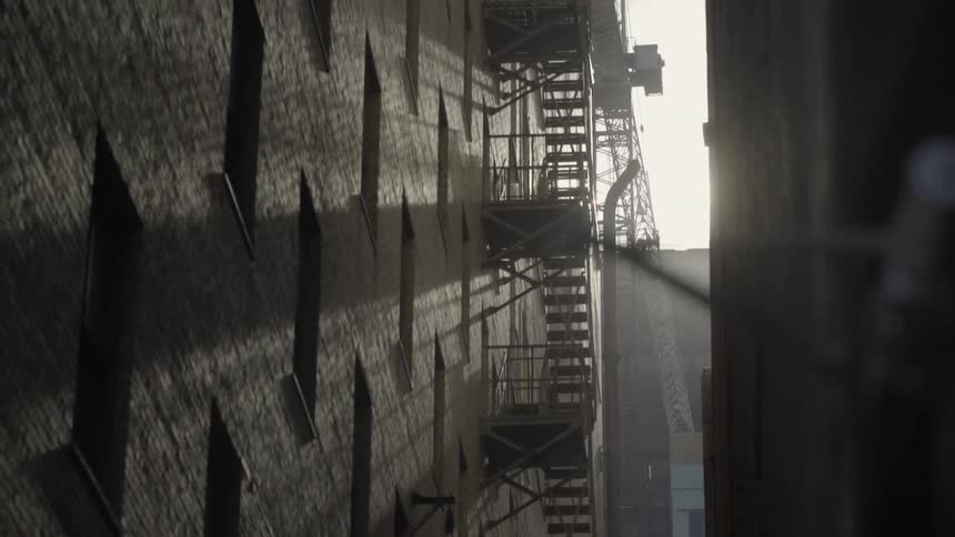 Sunlight creates shadows and sun-rays against a building with a fire-escape