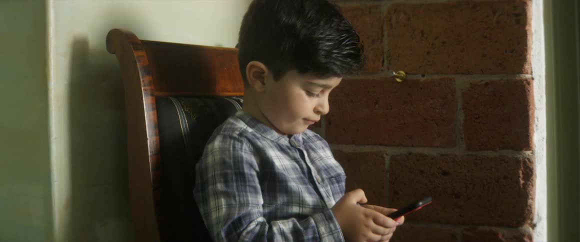Child sitting on chair playing on phone