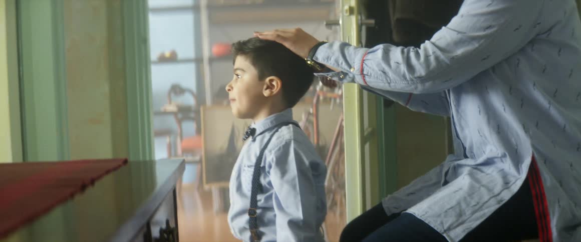 A woman sitting in a room combing a boys hair