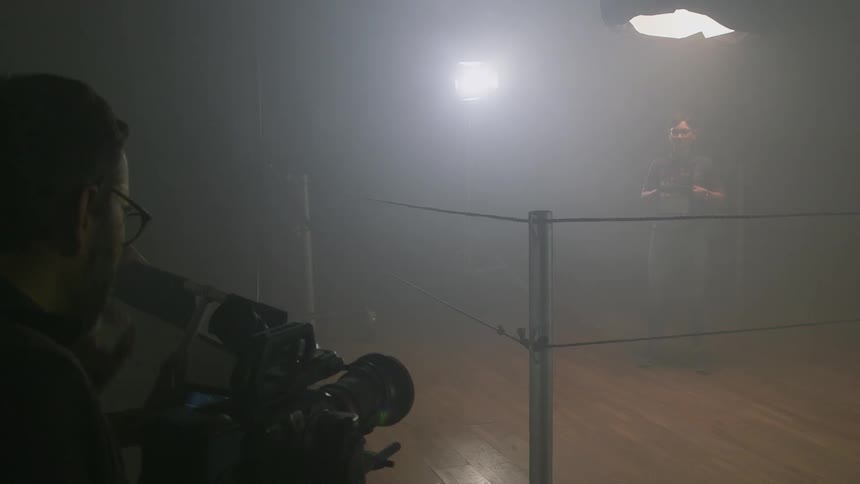 A man posing inside of a boxing ring as his picture is taken