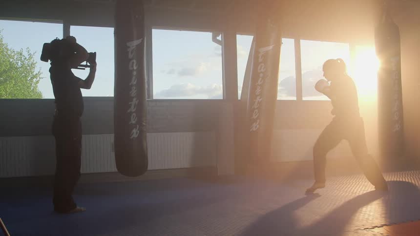A cameraman films a female boxer as she works out in a gym