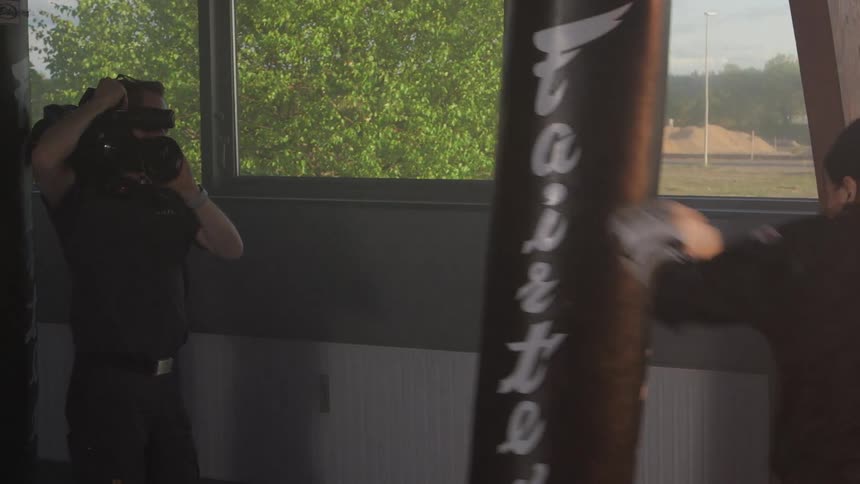 A cameraman films a female boxer as she punches a bag