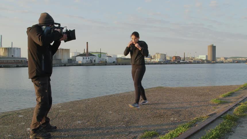 A photographer films a woman who is going through kickboxing moves