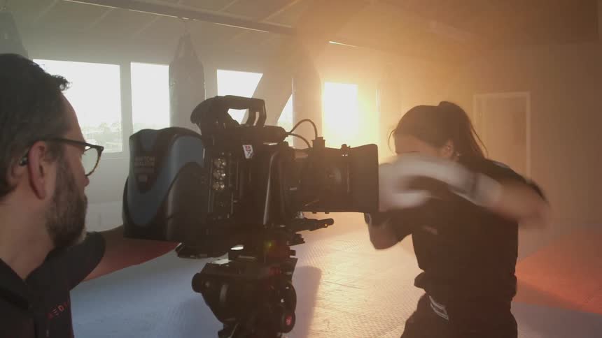 A woman spars in front of a camera and camera man