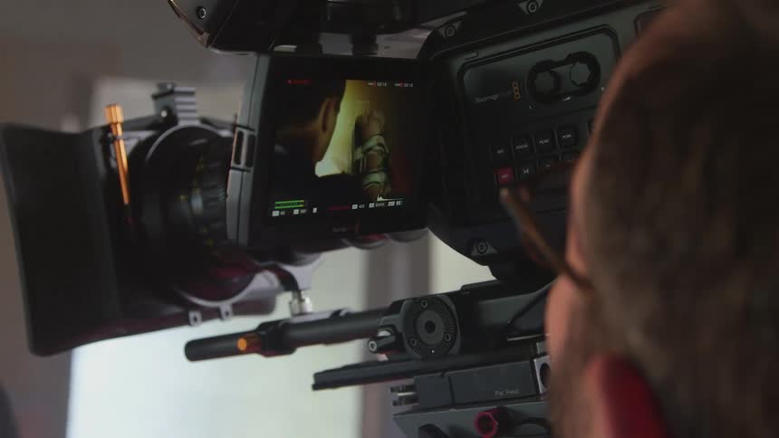 A photographer watches the monitor on his camera as he films a boxer