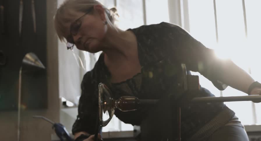 A woman molds hot glass