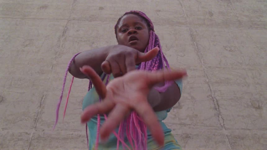 Young long haired woman energetically dancing in front a concrete wall