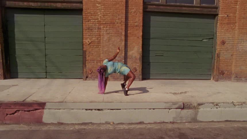 A woman is dancing outdoors by a building