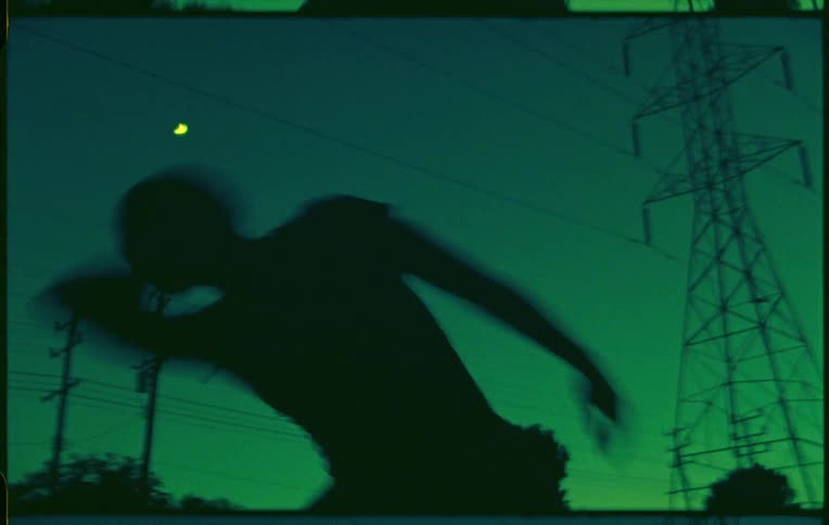 A dancer frantically dancing near power lines and transmission towers under the full moon on a green sky