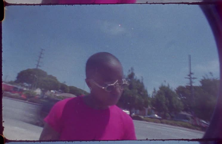 A young girl stands next to the road as cars drive past