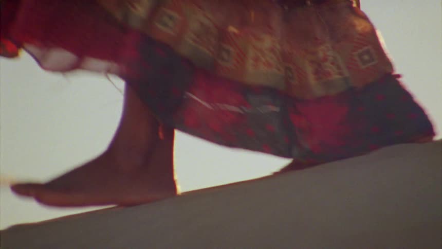 A woman walks along a sandy hill