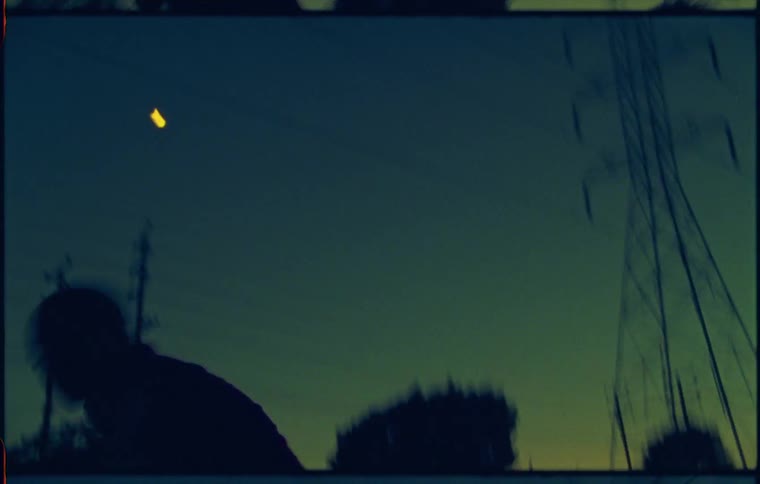 A silhouette of a person dancing with trees utility poles the moon the sky and clouds in the background
