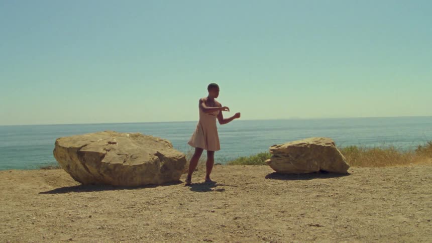 A teenager dances on the shore