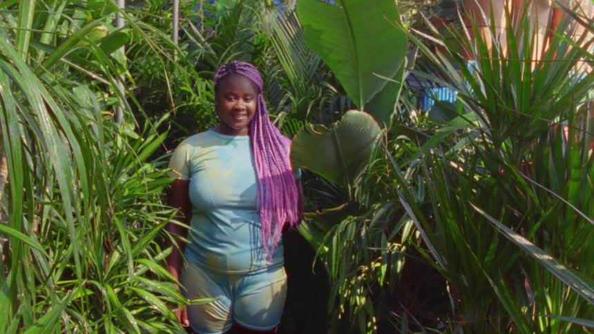 Woman standing in the green folliage looking at the camera smiling