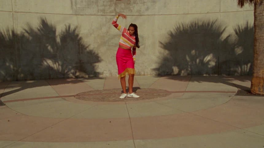A woman is dancing outdoors during the day
