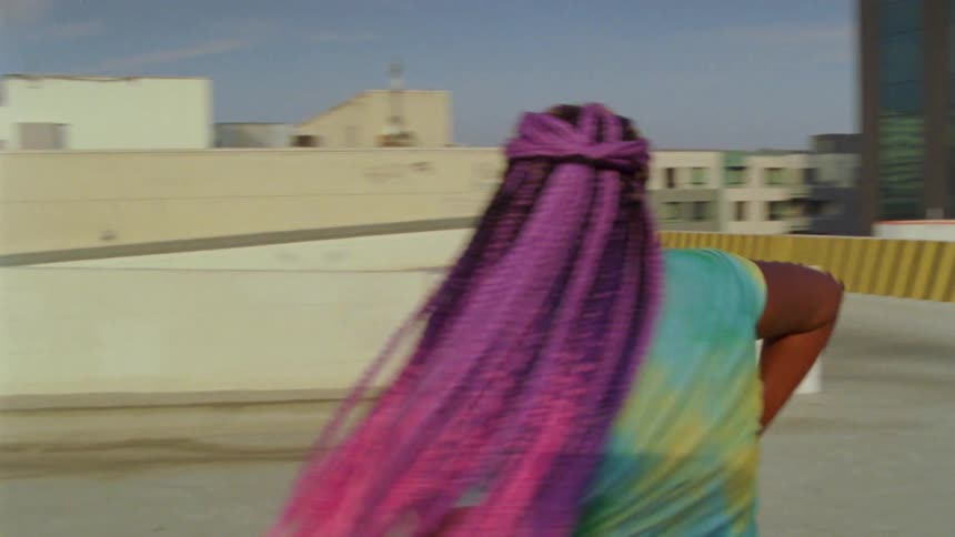 A young woman dances in a parking lot on the roof of a parking garage in a metropolis during the day