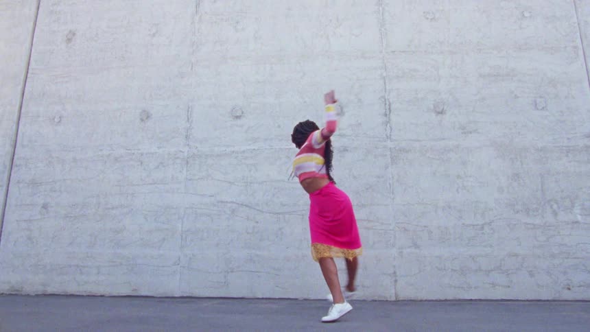 Young long haired woman energetically dancing in front a concrete wall