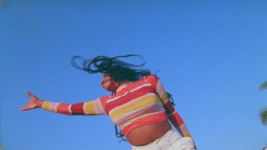 A woman is jumping around dancing outside