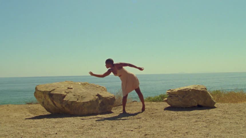 A woman that is dancing around on a cliff