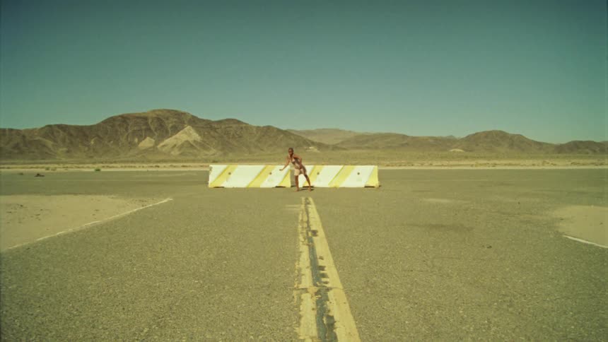 Woman dancing in front of the concrete barriers in the road near the mountains