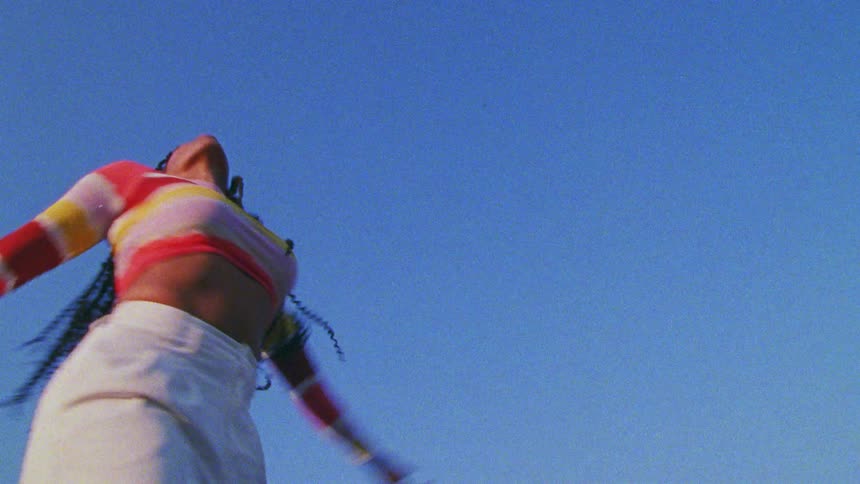 A young woman dances under the clear blue daytime sky