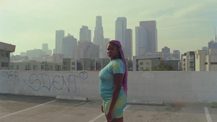 A woman is standing on a roof of a building in a downtown city