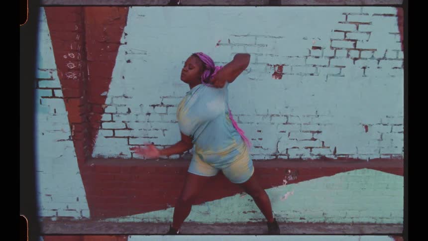 A woman dancing in front of a wall