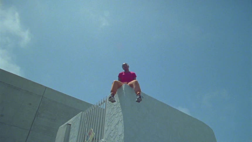 A teenage girl sits on the roof of a building