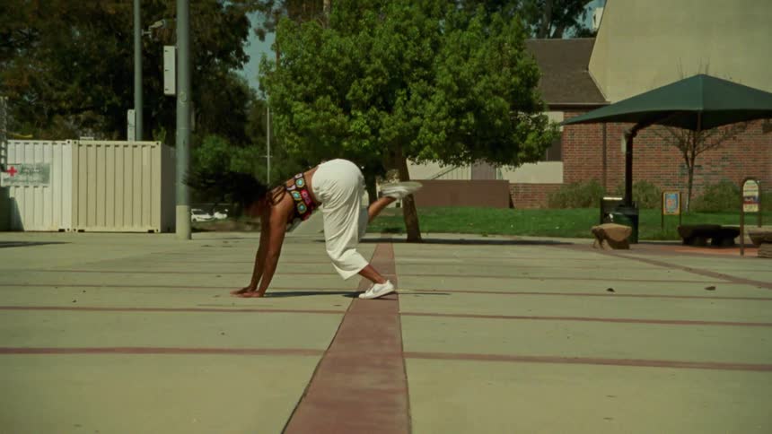 A teenage girl dances in a park
