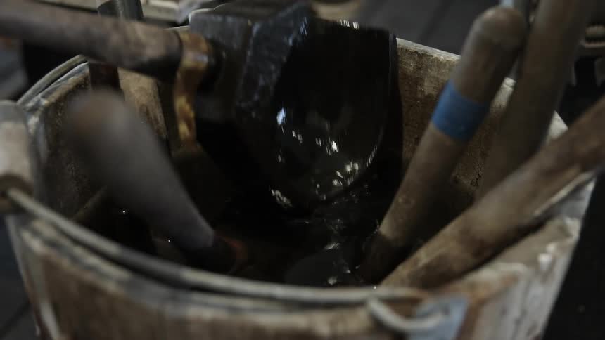 A tool is put into a wood bucket filled with water and other tools