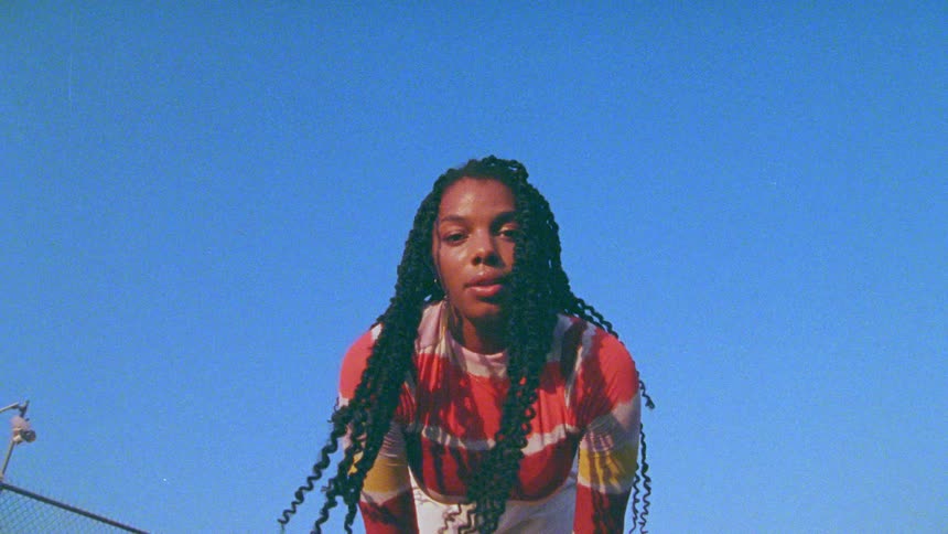 Young long haired woman looking at the camera against a clear blue sky