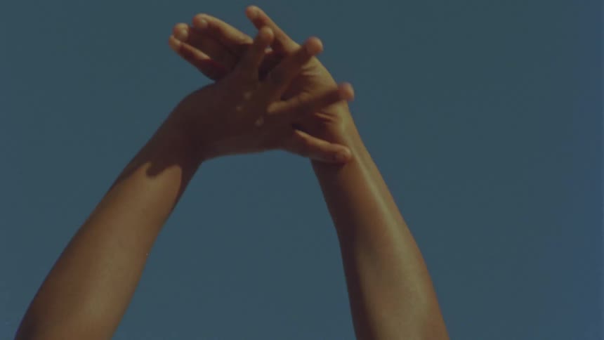 Close up of a females arms raised in the air as she rubs her arms and hands together