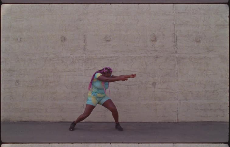A woman dancing with a wall in the background