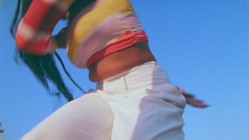 Young long haired woman energetically dancing in front of a blue sky