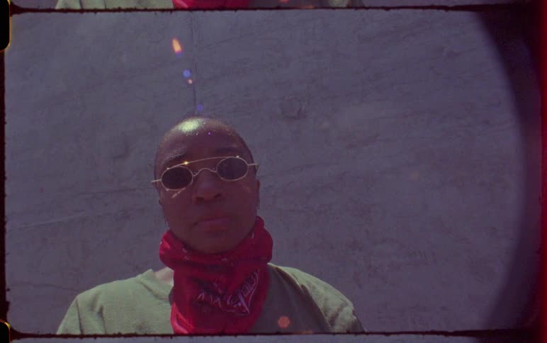 Woman wearing a face mask and sunglasses in front of a concrete wall