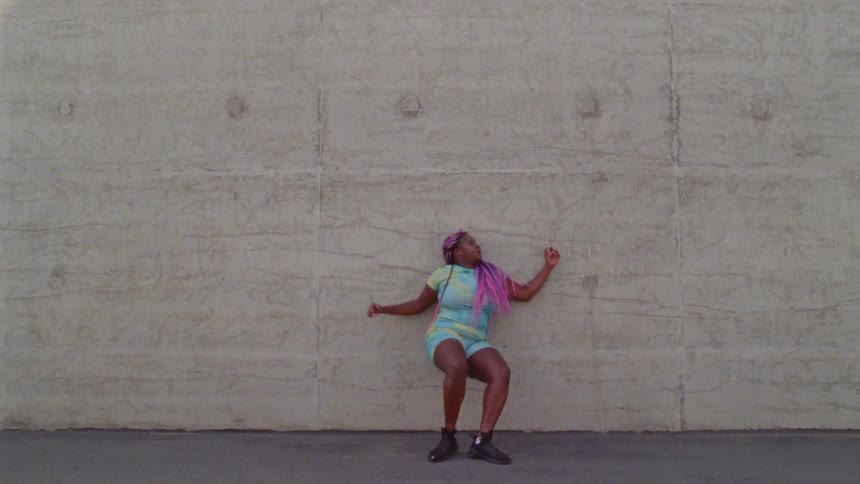 A woman with purple dreadlocks dances outside