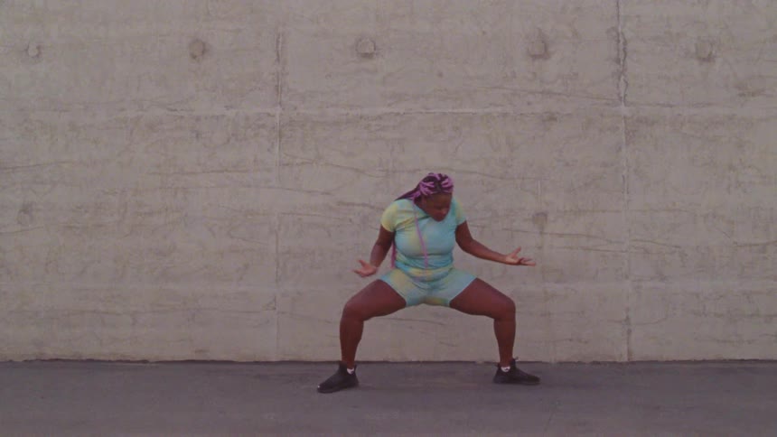 Young long haired woman energetically dancing in front a concrete wall