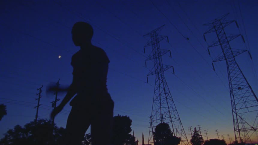 A woman dancing around at night under power lines