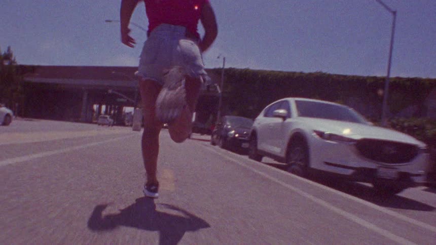 A bald woman running in the middle lane of a highway