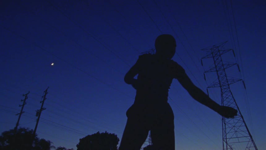 Silhouette of a dancer near power lines and transmission towers under the full moon at evening