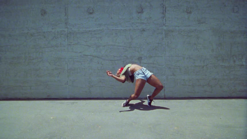 A woman dancing with a wall in the background