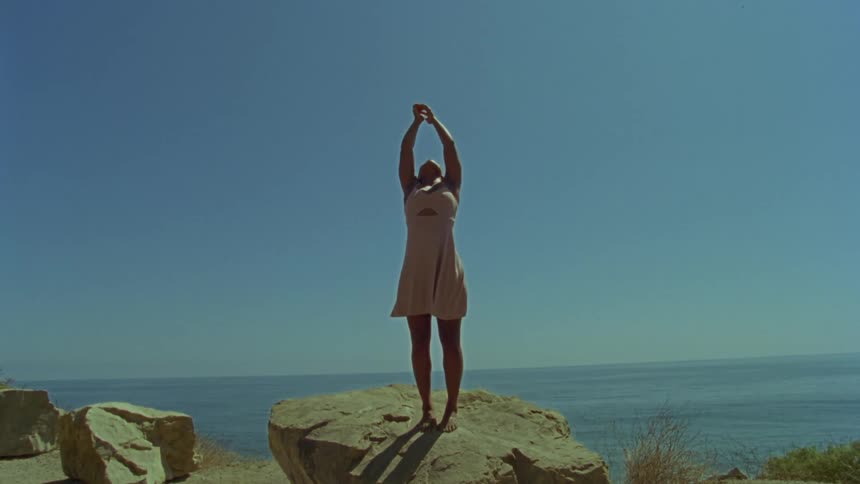 A woman that is dancing outside on a rock