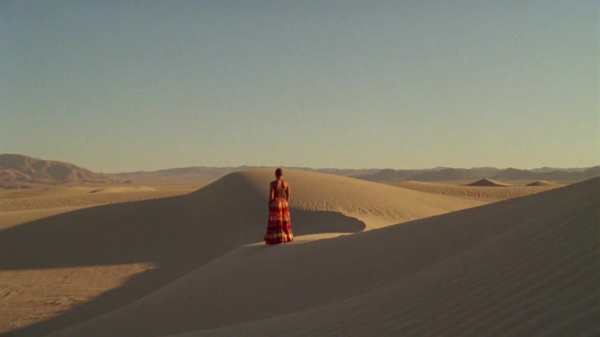 Woman walking down a hill of yellow sand in a desert at daytime