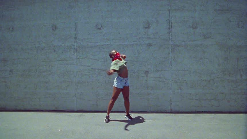 A woman is dancing by the tall wall