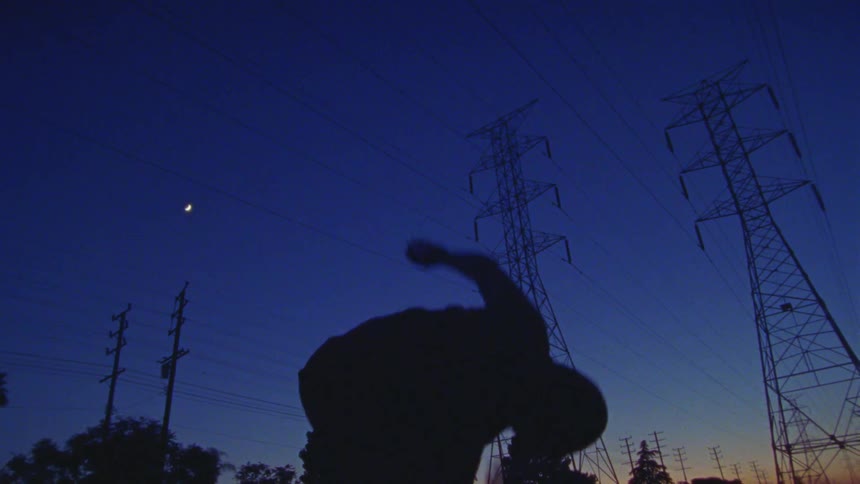 A person is dancing outdoors in a rural area at night