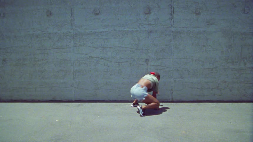 A teenage girl dances on concrete outside