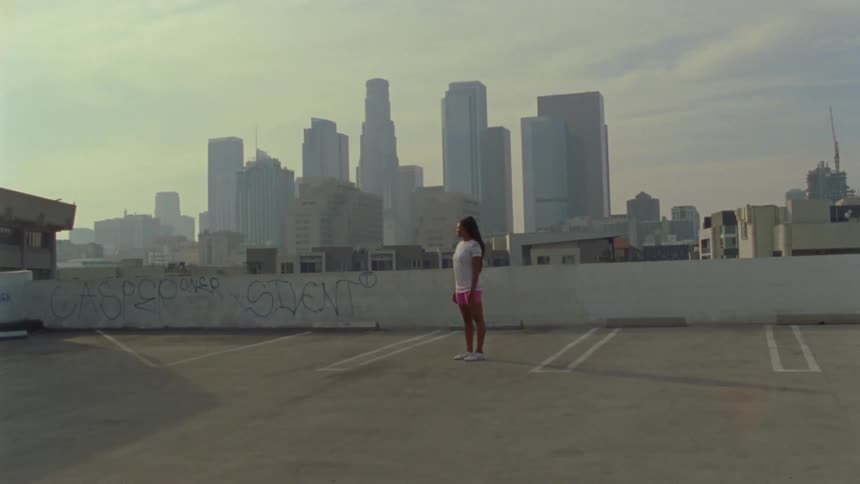 A woman is standing on a roof in a downtown city