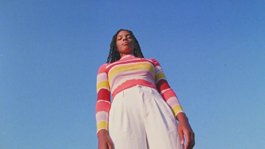 Footage of a woman standing outdoors is displayed